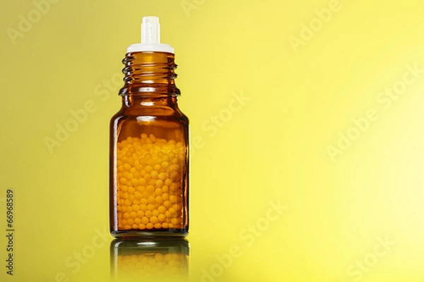 Obraz single bottle with homeopathy globules with yellow background