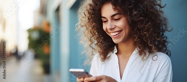 Fototapeta Close up of a woman smiling while holding a smartphone and talking in a stock photo