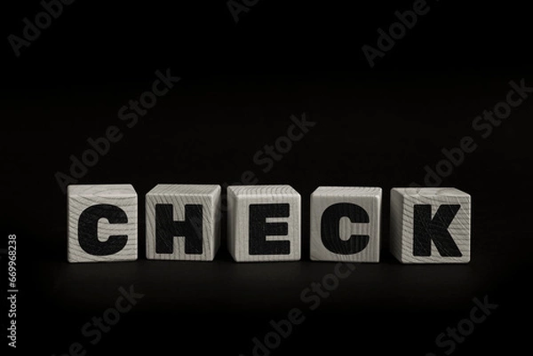 Fototapeta Word CHECK written with wooden cubes. Studio shot of some arranged wooden blocks with a textual message.