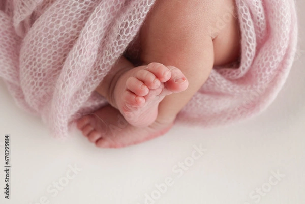 Fototapeta Close-up of tiny, cute, bare toes, heels and feet of a newborn girl, boy. Baby foot on pink soft coverlet, blanket. Detail of a newborn baby legs. Macro horizontal professional studio photo. 
