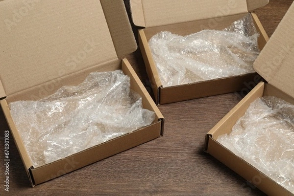 Fototapeta Many open cardboard boxes with bubble wrap on wooden table