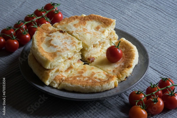Fototapeta Homemade cheese filled savoury pies khachapury on grey plate served with tomatoes. Selective focus