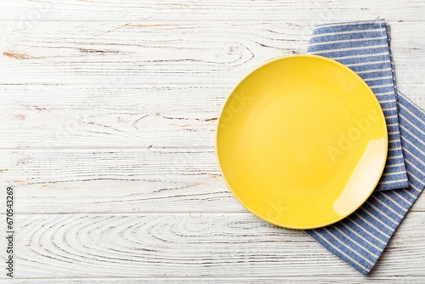 Obraz Top view on colored background empty round yellow plate on tablecloth for food. Empty dish on napkin with space for your design