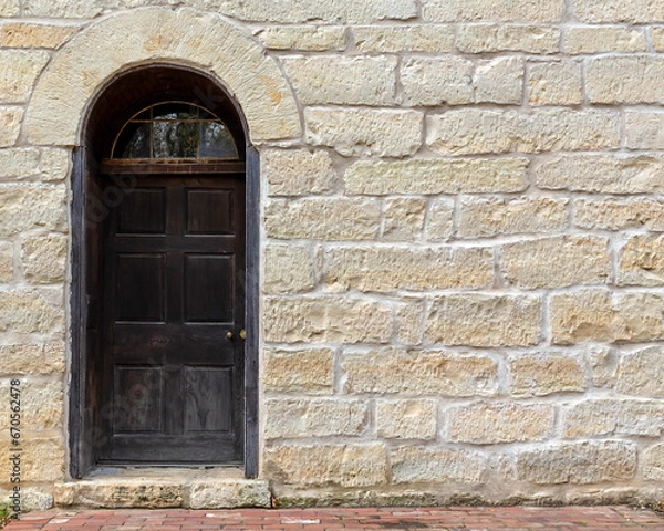 Fototapeta vintage stone brick wall with an antique door exterior building background texture
