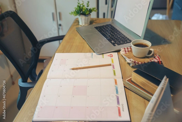 Obraz Agenda, planner book, laptop, 2024 calendar, pencil, and cup of coffee place on business office desk. Diary for organizer to plan timetable, daily appointment, and management job at room.