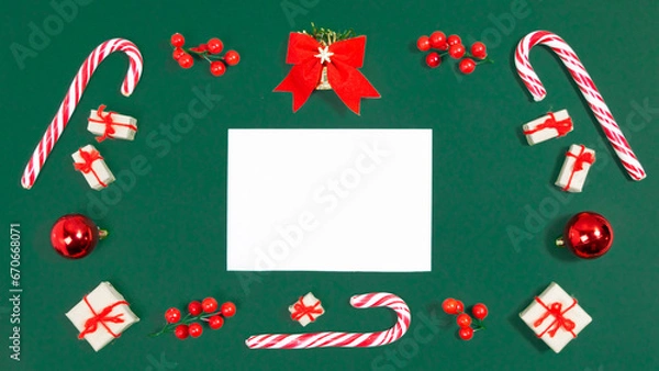 Fototapeta Christmas greeting card. Rectangular frame of candy canes, christmas balls, twigs with red berries and gifts boxes on viridian green background. Template for text. Copy space.