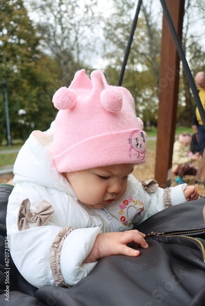 Obraz dad holds a little girl in his arms and rides on a swing in the park in autumn
