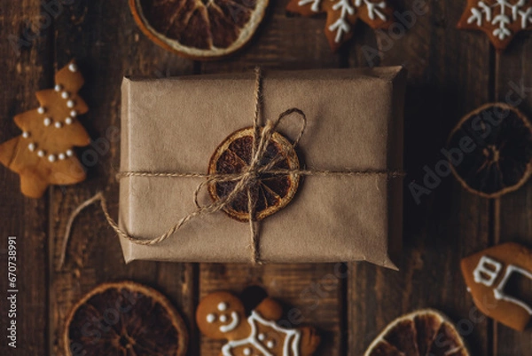 Fototapeta Zero waste Christmas wrapping. Simple new year gift in craft paper on rustic wooden background with gingerbread cookies. Plastic free sustainable lifestyle flat lay top view