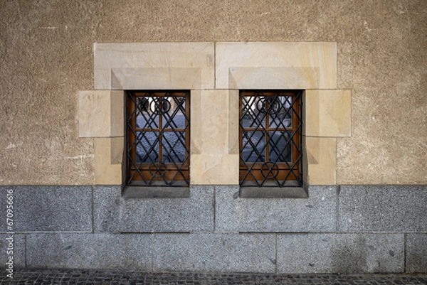 Fototapeta Two windows of the old building secured with bars. Windows set in a band of large stone blocks.