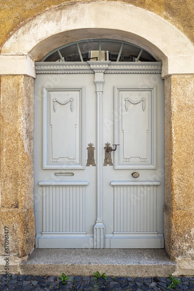 Fototapeta Wooden ornate arched entrance door to the building set in a stone wall.