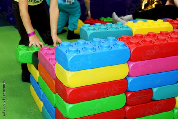 Fototapeta a child builds a wall of colorful toy building blocks in a children's center