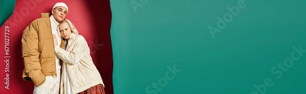 Fototapeta banner of romantic couple in winter jackets standing together near torn turquoise and red background