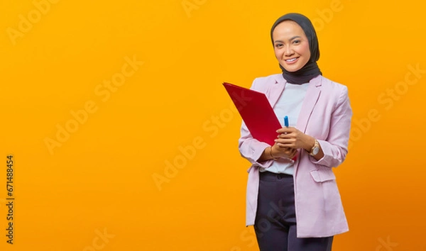 Fototapeta Beautiful asian woman holding folders and pen while looking at c