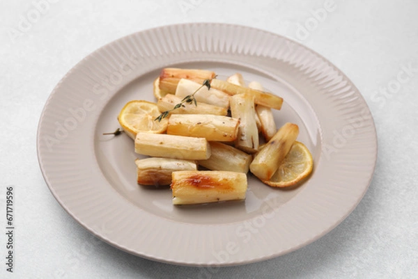 Fototapeta Plate with baked salsify roots, lemon and thyme on light grey table, closeup