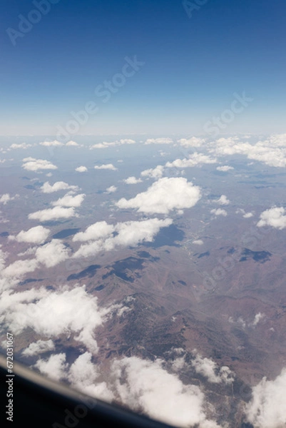Fototapeta Beautiful view from the airplane window from above to the clouds, mountains, roads, rivers. Picturesque landscape from a helicopter window on a sunny day.