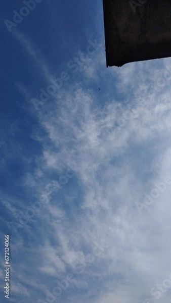 Fototapeta Photo of a bright blue sky with a few clouds like smoke