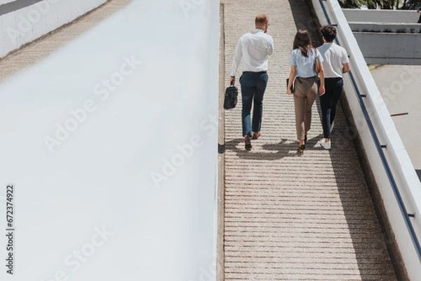 Fototapeta Three young businesspeople walking down the path turned backwards talking to each other