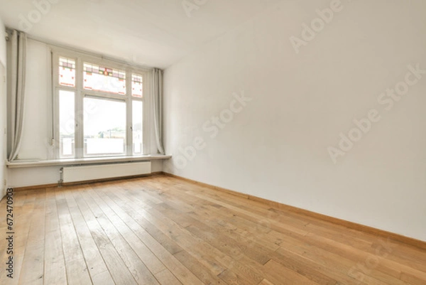 Fototapeta an empty room with wood flooring and white walls in the background is a large window that looks out onto the street