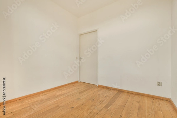 Fototapeta an empty room with white walls and wood flooring on the right, there is a door in the corner