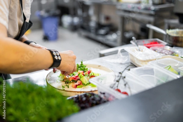 Obraz Chef cooking Green salad with salmon, cucumbers, lettuce, spices, caviar on restaurant kitchen