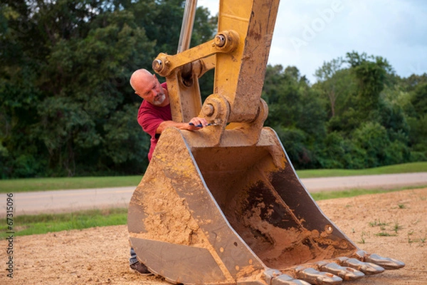 Obraz Man working on backhoe bucket