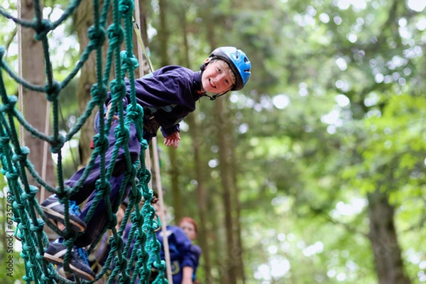 Fototapeta Happy boy enjoying a climbing adventure in activity park
