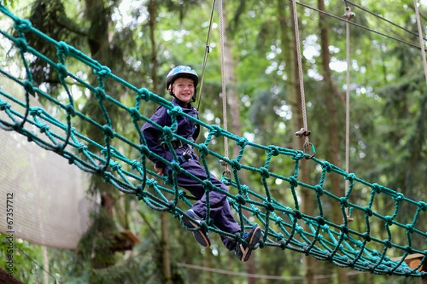 Fototapeta Happy boy enjoying a climbing adventure in activity park