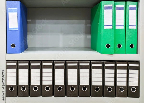 Fototapeta blue, green and blac binder folder wit different size on rack
