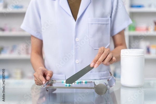 Obraz Close up of female pharmacist counting and arrange pills on qualified stainless counting tray with spatula in pharmacy. Pharmacist prepare medication in stainless tray by prescription at drugstore.