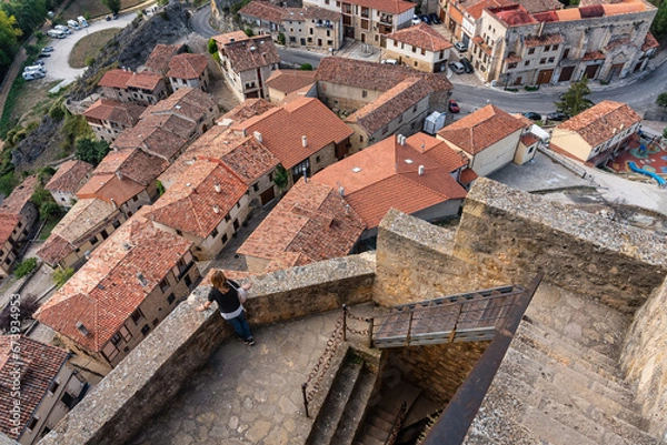 Fototapeta Tourist woman contemplating the rooftops of the medieval village from the top of the wall, Frias, Burgos.