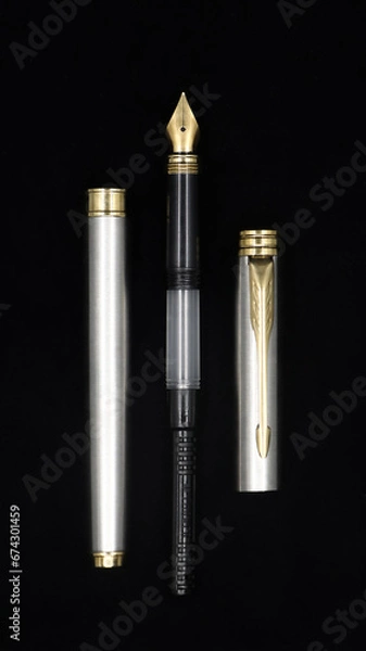 Fototapeta parts of a luxury antique fountain pen assembled in pieces and isolated in a black background