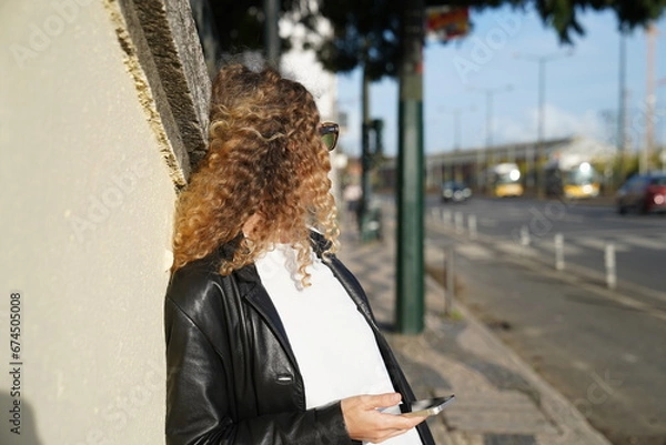Fototapeta person walking on the street and waiting for a taxi while holding smartphone