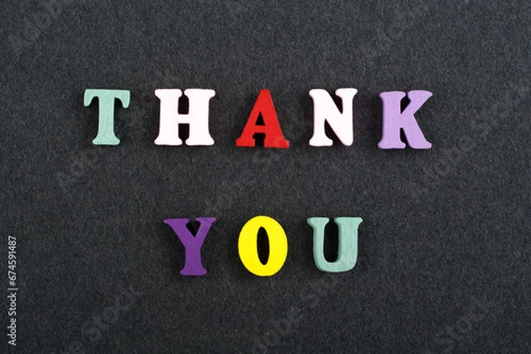 Fototapeta THANK YOU word on black board background composed from colorful abc alphabet block wooden letters, copy space for ad text. Learning english concept.
