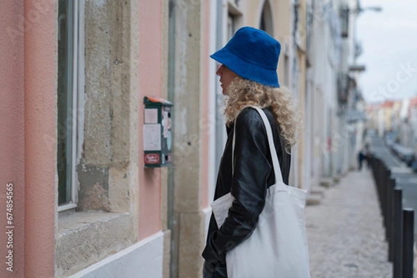 Obraz woman standing on a path of lisbon in portugal and looking in a window on a bright and pink street