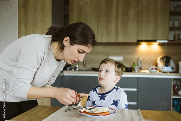 Obraz Mother with son having breakfast in the kitchen