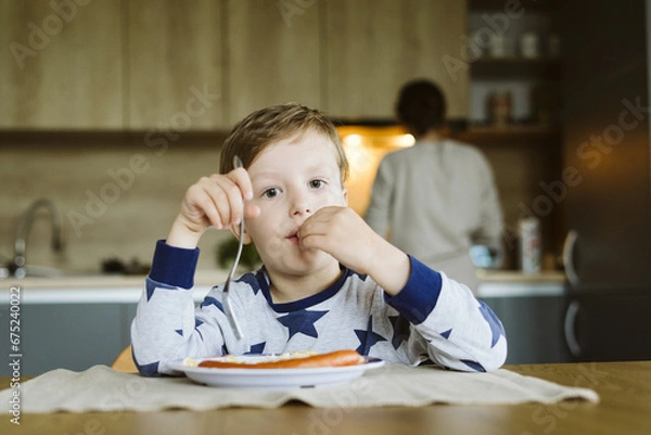 Obraz Portrait of a little boy having breakfast in the kitchen at home