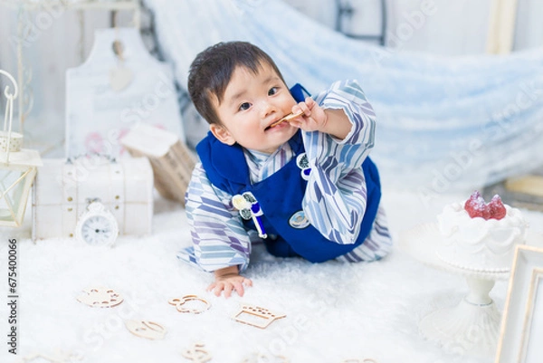 Fototapeta バースデーフォトセットで1歳の誕生日をお祝いして選び取りをする和服姿の可愛い赤ちゃん