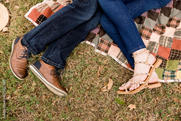 Obraz A romantic shot of a couple's feet - a man and a woman - lying on a quilted blanket in the fall season