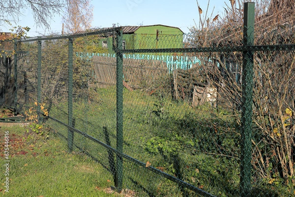 Fototapeta Fence made of steel mesh with a polymer coating near an abandoned cottage
