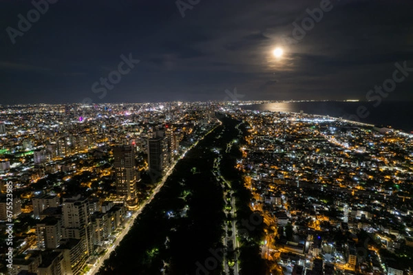 Obraz Beautiful aerial Night view of the illuminated  city of Santo Domingo - Dominican Republic with is Parks, buildings, suburbs ,turquoise Caribbean ocean, parks and malecon
