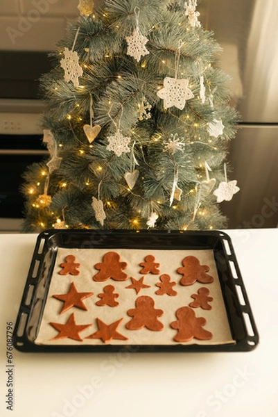 Fototapeta Cut out Christmas cookie dough shapes on a baking sheet.