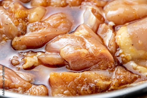 Obraz 鶏肉の唐揚げ調理シーン。鶏もも肉に下味をつけるため、タレに漬け込む。

