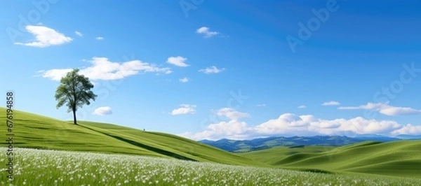 Fototapeta A serene and minimalist background landscape featuring rolling green hills, and soft, fluffy clouds in the vast sky, creating a tranquil and peaceful atmosphere. Photorealistic illustration