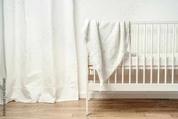 Fototapeta Cotton baby blanket with paper tag hanging from baby bed