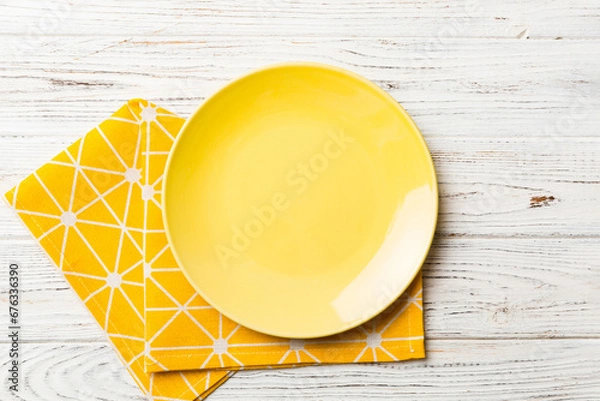 Obraz Top view on colored background empty round yellow plate on tablecloth for food. Empty dish on napkin with space for your design