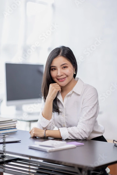 Fototapeta Asian Business woman using calculator and laptop for doing math finance on an office desk, tax, report, accounting, statistics, and analytical research concept
