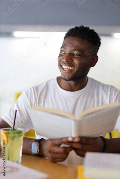 Obraz Happy young student in a library, surrounded by books, exuding confidence and representing the joy of education.