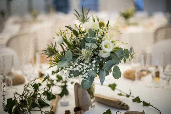 Obraz Un bouquet de fleur de mariage posé sur une table dressée avec une nappe blanche et de la porcelaine