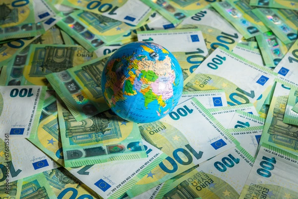 Fototapeta A little globe map lying on an assortment of euro money bills