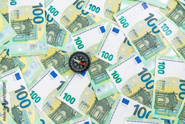 Obraz  A little compass shown from above on many 100 euro money bills, making a right choice concept
